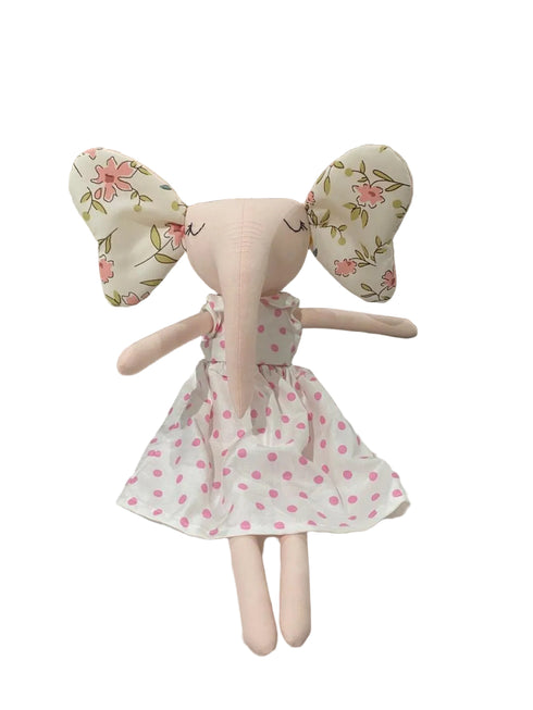 Stuffed animal toy with floral ears and a white dress with pink polka dots on a light surface.
