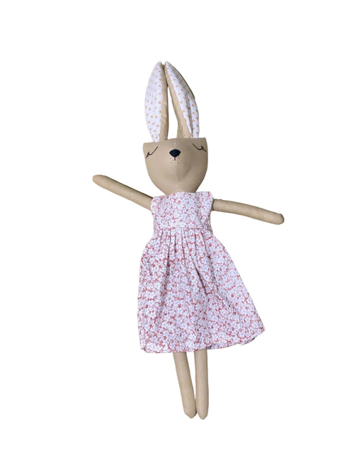 Handmade rabbit doll with a floral dress on a wooden surface