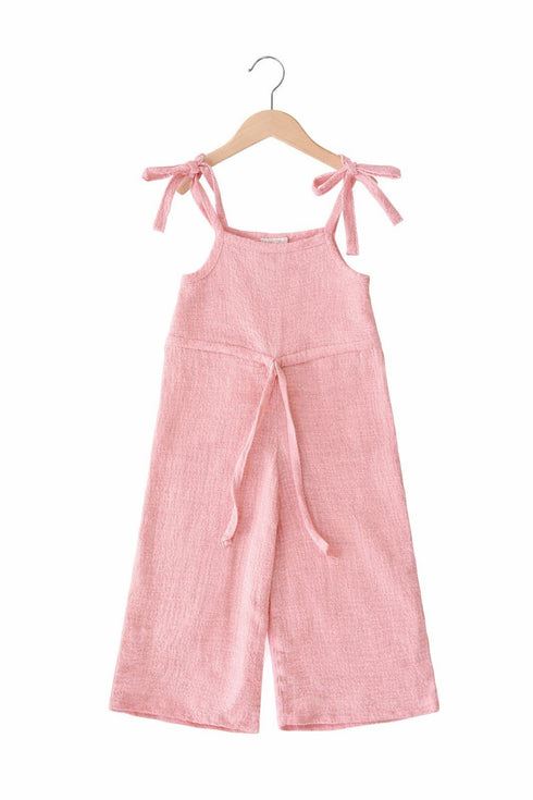 Pink jumpsuit with bow straps on a hanger against a white background