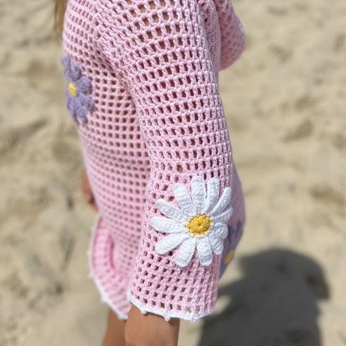 Pink crochet dress with floral details on a sandy background