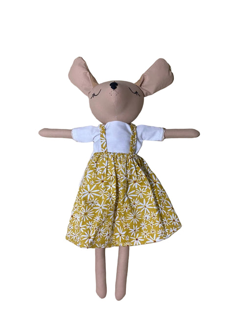 Stuffed puppies toy wearing a yellow dress with white patterns on a white background